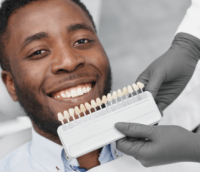 Dentist matching crown to color of mans teeth.